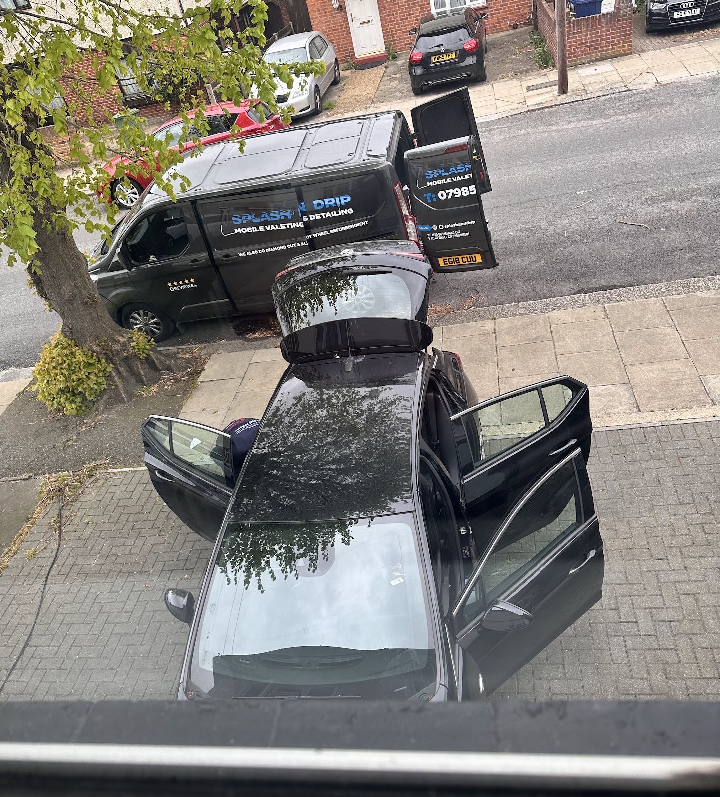 A white Rolls-Royce raised on the ramp inside Splash N Drip on Green Lanes, under the workshop sign